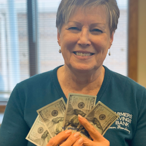 A woman from Farmers Savings Bank holding 100 dollar bills