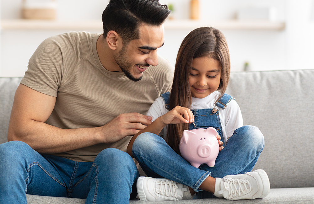 father and daughter putting coins in piggy bank